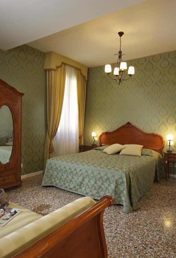 dettaglio camera da letto tripla con parete damascata verde